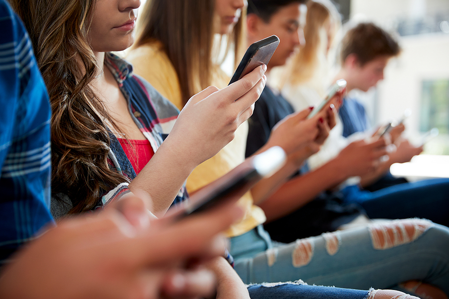 Close Up Of A Line Of High School Students Using Mobile Phones - Alpha