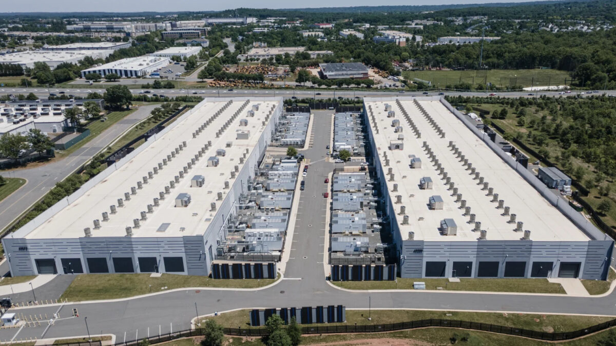 Aerial view of a large warehouse complex with two long white buildings separated by a central road and loading bays in between.