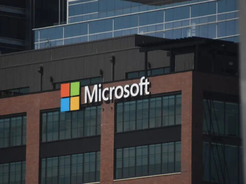 intro-1793034359 1 - Alpha Microsoft logo on a brick office building with glass windows in the foreground.